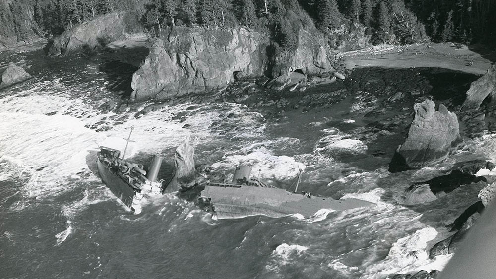 Black & white photo of the capsized and split General M.C. Meigs along the rocky shoreline of Olympic Coast National Marine Sanctuary