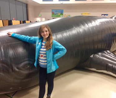 americorps service corps member posing with a humpback whale replica